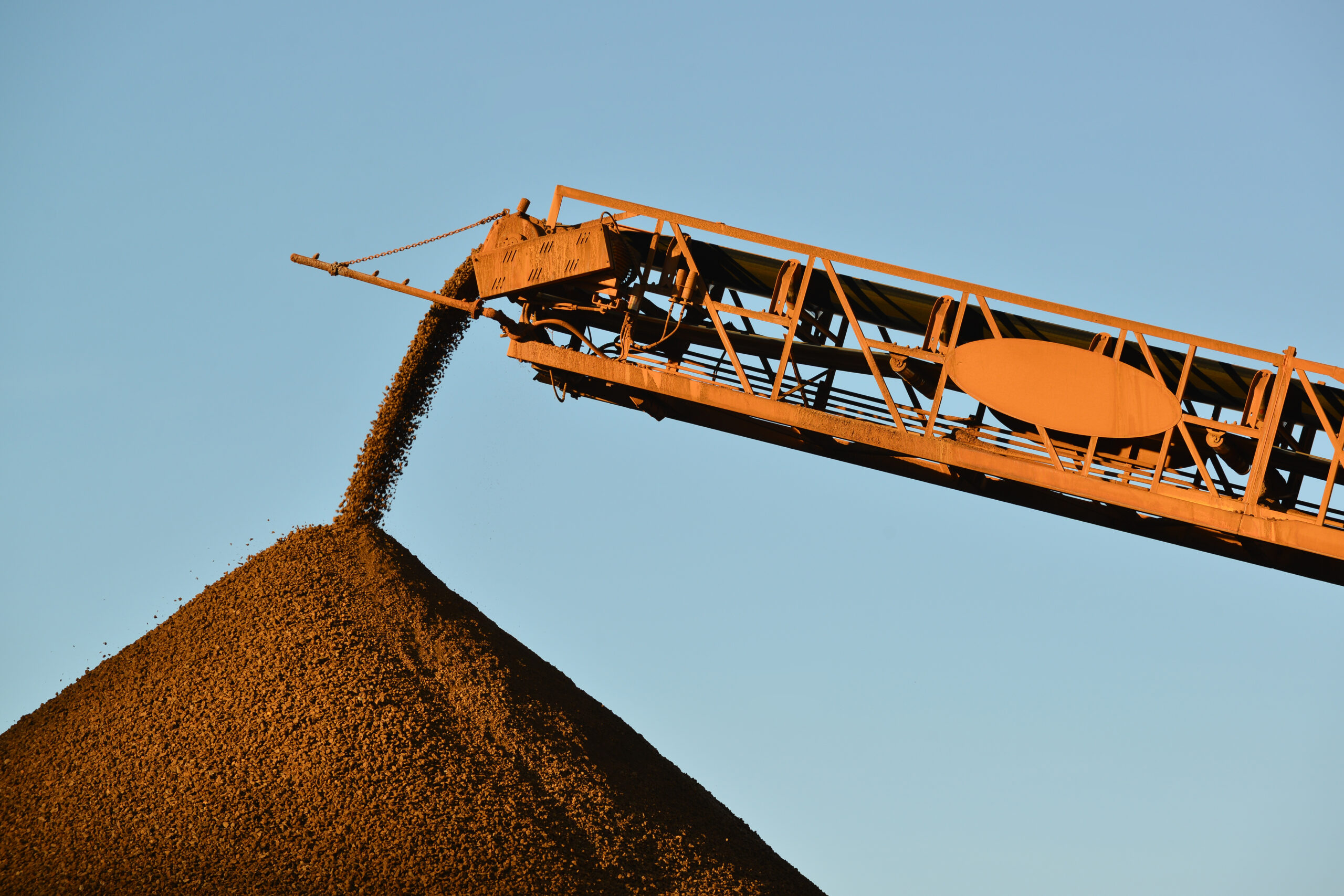 A conveyor belt dumps crushed ore on a stockpile at a mine site.